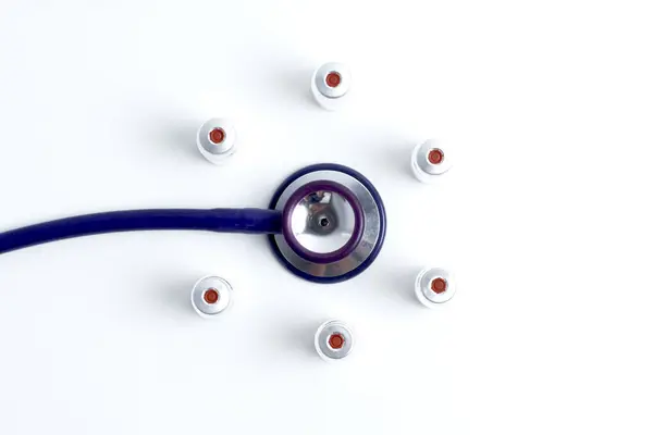 Beyaz arka planda tıbbi düzen, düz. Stetoskop ya da fonendoskop, aşı şişesi, şırınga fotokopi alanı, mesaj için yer. beyaz izolasyon tıbbi ekipmanları.