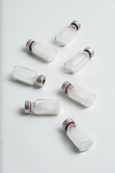 Beyaz arka planda metin boşluğu olan aşı şişelerinin düz hali. Aşı tüplerinin bembeyaz arka planı, sağlık tıbbi konsepti.