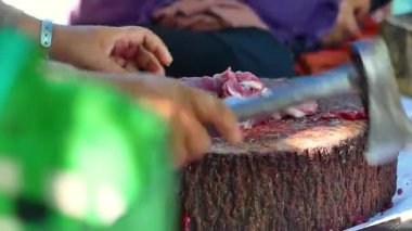 Bir grup kadın bayram kutlaması sırasında tahta tepside bir keçi eti yığınını bıçakla kesiyorlar. Kasap çiğ keçi etini bıçakla keser. Ied al adha kavramı.