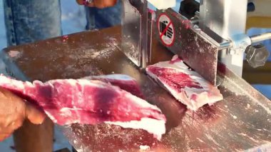 Kasap eti özel bir testere makinesiyle keser. Özel et testeresi makinesiyle kesilmiş sığır eti. Kurban Bayramı 'nda bir makineyle et kesme olayı.