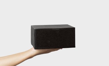 Kadın, beyaz arka planda siyah bükülmüş kutuyu tutuyor. Beyaz izole edilmiş arka planda küçük kahverengi dikdörtgen kutu tutan genç bir kadın..