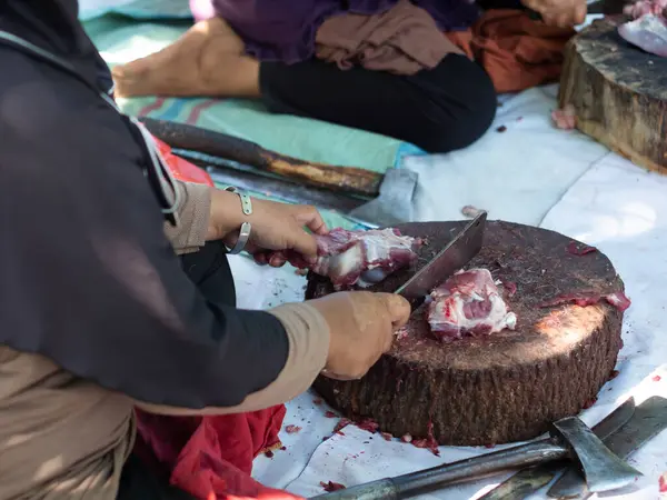 Bir grup kadın bayram kutlaması sırasında tahta tepside bir keçi eti yığınını bıçakla kesiyorlar. Kasap çiğ keçi etini bıçakla keser. Ied al adha kavramı.
