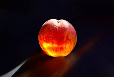 Siyah arka planda olgun kırmızı şeftali. Güneş ışınlarına yakın, yanan şeftali