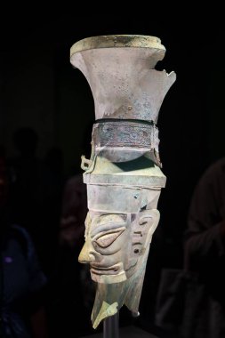 Guanghan China - May 24 2024: A  Bronze head statue with ritual vessel (known as Zun) on the head in exhibit of ancient artifacts at the Sanxingdui Museum in Sanxingdui near Chengdu, Sichuan Province in China. clipart