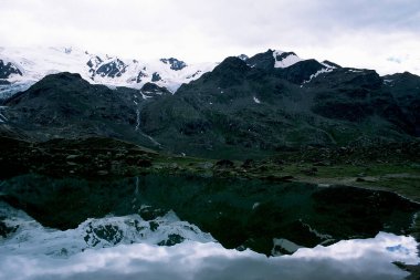 Güzel alp gölü karla kaplı bir dağ profilini yansıtıyor.