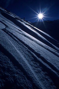 Güneşe karşı çekilen karı tasvir eden ve düşük mavi tonlarla güçlü kontrast etkiler yaratan velvia 50asa slaytında yapılmış sanatsal bir resim.