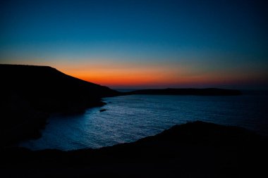 Girit, Sitia yakınlarındaki bir körfezde gün batımında, günün son renkleri denize yansıyor.