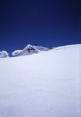 Güneşe karşı çekilen karı tasvir eden ve beyaz kar ve gökyüzü arasındaki kontrastın az görünen mavi tonlarıyla grafik efektlerini yaratan velvia 50asa slaytında yapılmış sanatsal görüntü.