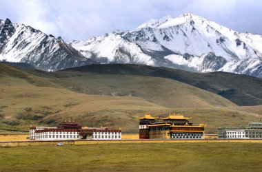 Açık hava manzarası: Tibet 'in güzel Budist tapınağı tipik altın çatılı Tagong, Sichuan' daki karlı manzaraya karşı duruyor.