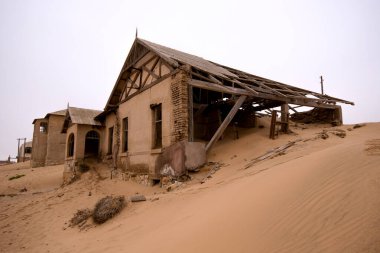Namibya 'nın eski maden kasabası Kolmanskop' ta terk edilmiş bir sanayi binası yıkılmış duvarlar ve iç kısımları kumla kaplanmış.