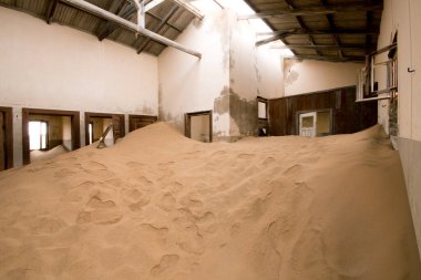 Namibya 'nın eski maden kasabası Kolmanskop' ta terk edilmiş bir sanayi binası yıkılmış duvarlar ve iç kısımları kumla kaplanmış.