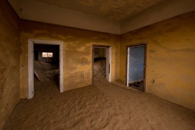 Namibya 'nın eski maden kasabası Kolmanskop' ta terk edilmiş bir sanayi binası yıkılmış duvarlar ve iç kısımları kumla kaplanmış.