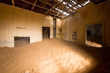 Namibya 'nın eski maden kasabası Kolmanskop' ta terk edilmiş bir sanayi binası yıkılmış duvarlar ve iç kısımları kumla kaplanmış.