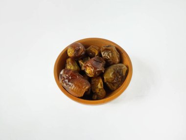 Tahta bir kasenin içindeki taze tarihler beyaz arka planda izole edilmiş..