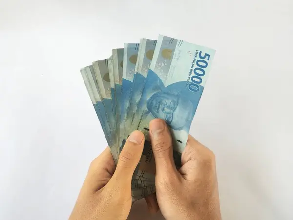 stock image Hand holding several Indonesian banknotes, worth 50,000 Rupiah and isolated with a white background.