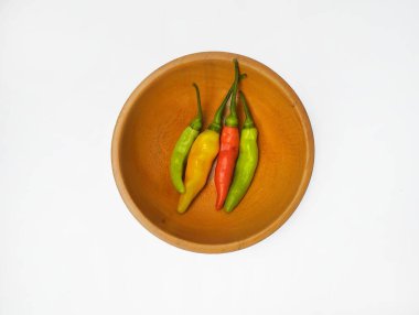 Ahşap bir kasede beyaz arka planda izole edilmiş kırmızı biberler..