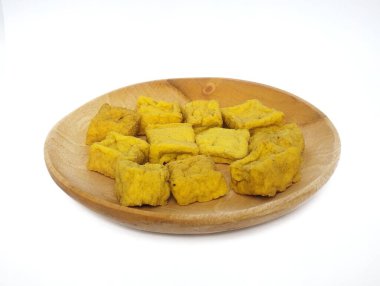 Tahta tabakta çiğ sarı tofu ya da sarı tofunun yakın plan görüntüsü, beyaz arka planda izole edilmiş..
