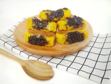 Tahta tabakta çikolata aromalı kusmuk keki ve beyaz arka planda izole edilmiş kareli taban.. 