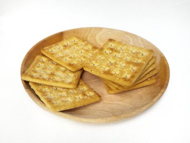 Tahta bir tabakta, beyaz arka planda izole edilmiş kare bisküviler..