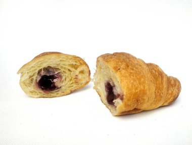 Tahta bir tabakta çeşitli meyve reçeli ile dolu kruvasan ekmeği, beyaz bir arka planda izole edilmiş..