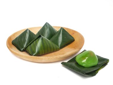 Bugis keki, geleneksel Endonezya aperatifi yumuşak yeşil yapışkan pirinç un keki, tatlı rendelenmiş hindistan cevizi ile doldurulmuş, muz yapraklarına sarılmış, ahşap bir tabakta, beyaz bir arka planda izole edilmiş