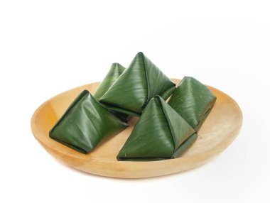 Bugis keki, geleneksel Endonezya aperatifi yumuşak yeşil yapışkan pirinç un keki, tatlı rendelenmiş hindistan cevizi ile doldurulmuş, muz yapraklarına sarılmış, ahşap bir tabakta, beyaz bir arka planda izole edilmiş