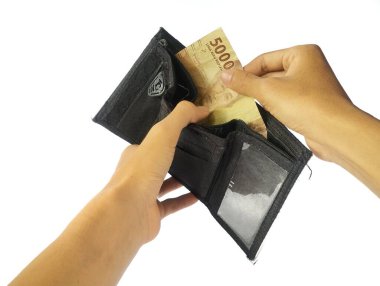 A man's hand takes and shows money from a wallet isolated on white background, rupiah is the currency of Indonesia clipart