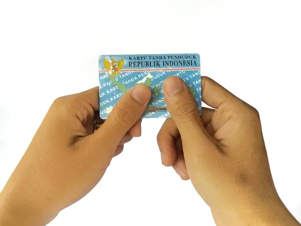 stock image Human hand holding an Indonesian identity card or KTP, isolated on a white background.