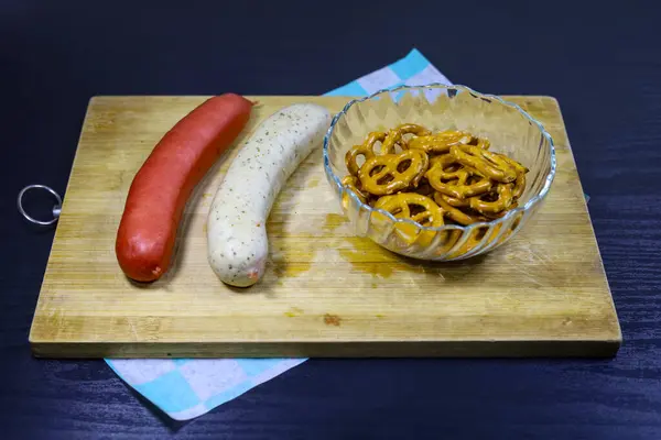 Kırsal ahşap tepside kristal bir krakerde çıtır krakerlerle birlikte iki geleneksel Alman sosisi resmi. Gastronomi, Alman mutfağı, Ekim Festivali ve geleneksel aşçılık temalarını resmetmek için mükemmel..
