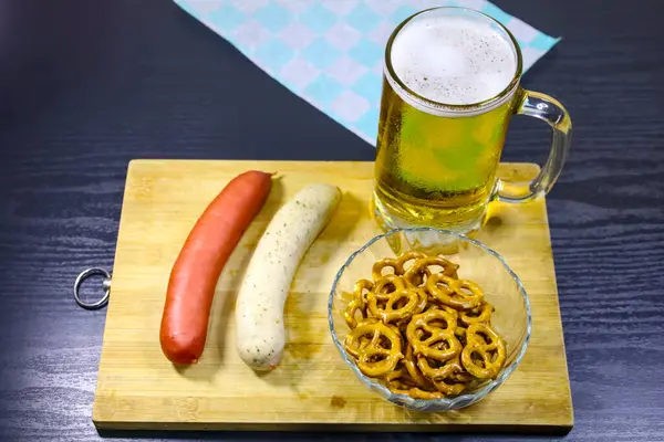 İki geleneksel Alman sosisi, kristal kasede çıtır kraker ve kırsal ahşap tepside Ekim Festivali temalı kağıt dolu bir bira bardağı. Alman mutfağının, Ekim Festivali şenliklerinin ve tra 'nın temaları için mükemmel.