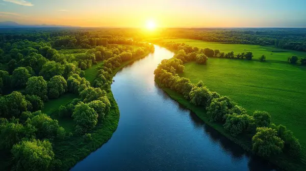 Aerial view of a river flowing through lush green fields at sunset.