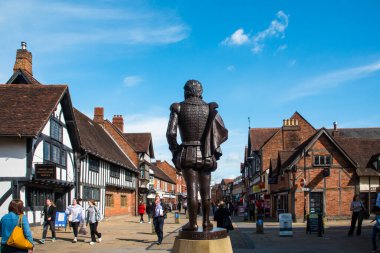 Stratford-upon-Avon, Warwickshire, İngiltere - 05: 30 2024 - Shakespeare heykeli, arkasından, İngiltere 'nin göbeğindeki turistik İngiliz doğum kasabasında bir ortaçağ caddesinin ortasında. Yüksek kalite fotoğraf