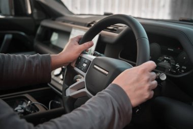 Warwickshire, Birleşik Krallık 09-18-2024 - araba sürüyor. Eller bir Land Rover Koruyucusunun direksiyonunda, yeni bir off road aracıyla yolculuğa başlıyor.. 