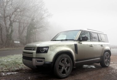 Warwickshire, İngiltere - 11 Ocak 2025: Land Rover Defender 110 X-Dynamic HSE PHEV Pangea 'da yeşil metalik boya ile iç İngiltere' de sisli bir günde kırsal alanda poz veriyor.