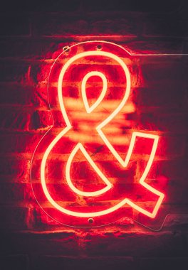 Ve 'nin sembolü, tuğla duvara karşı parlayan neon lambalı ampersand. Kötü ruh hali tipografisi dekorasyonu. Ayrıca kartlar ve sunumlar için yeni bir kavram ekle.