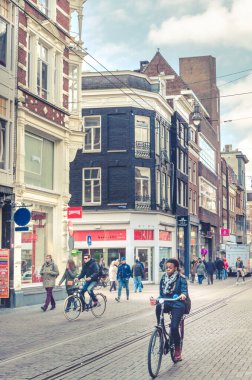 Amsterdam, Hollanda - 5 Nisan 2013 - Amsterdam sürdürülebilir şehir sokak yaşamı. Turistik Hollanda 'nın şehir merkezi. Bisikletçiler, yoldan geçenler ve eski geleneksel binalar..