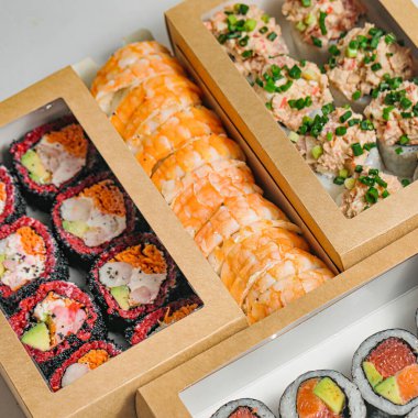 Masadaki ahşap bir kutuda sunulan maki dürüm ve nigiri de dahil olmak üzere çeşitli suşiler..