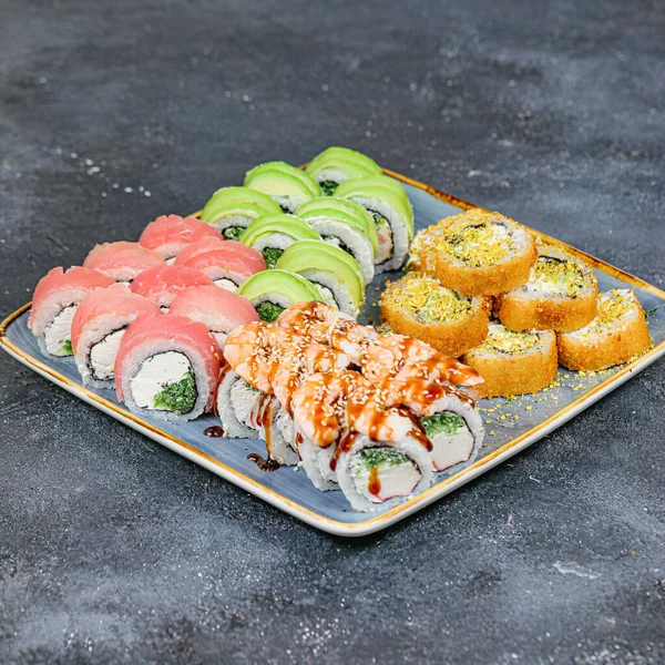A plate filled with a variety of sushi and rolls, neatly arranged on a table.