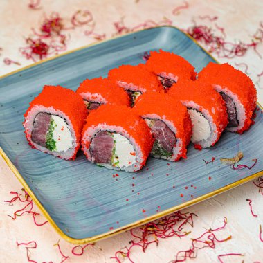 Bir tabak dolusu suşi rulosu ve ahşap bir masada sergilenen sashimi..