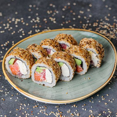 Tahta bir masaya yerleştirilmiş çeşitli suşi rulolarıyla dolu bir tabak..