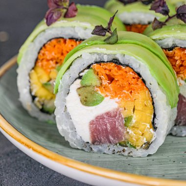 Bir tabak dolusu suşi rulosu, her birinin üzerinde çeşitli canlı sebzeler var..