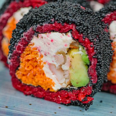 Canlı renkleri ve karmaşık dokuları vurgulayan taze suşi ruloları olan bir tabağın detaylı bir görüntüsü..