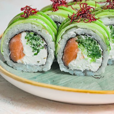 Wasabi ve zencefille süslenmiş taze ve ustalıkla hazırlanmış suşi dürümleriyle dolu bir tabağın yakın plan fotoğrafı..
