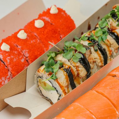 Suşi ve sashimi de dahil olmak üzere çeşitli suşilerle dolu bir kaç kutu lezzetli deniz ürünleri ve aromalar sergiliyor..