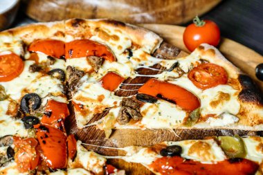 Ahşap bir tabağa yerleştirilmiş pizzanın detaylı bir görüntüsü, malzemelerini, kabuğunu ve sunumunu sergiliyor..