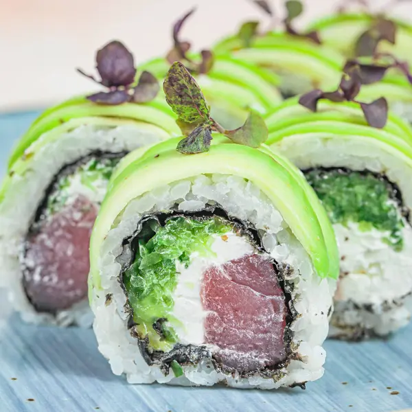 Mavi tabakta yeşil ve beyaz soslu suşi ruloları..