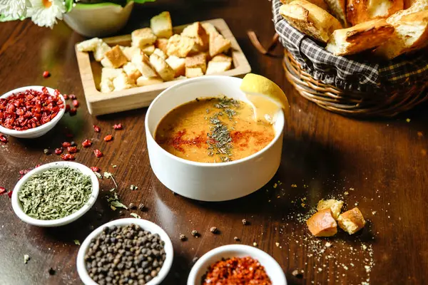 Lezzetli çorbayla dolu çeşitli kaseler ve bir dizi renkli, taze kesilmiş sebzelerle dolu bir masa..