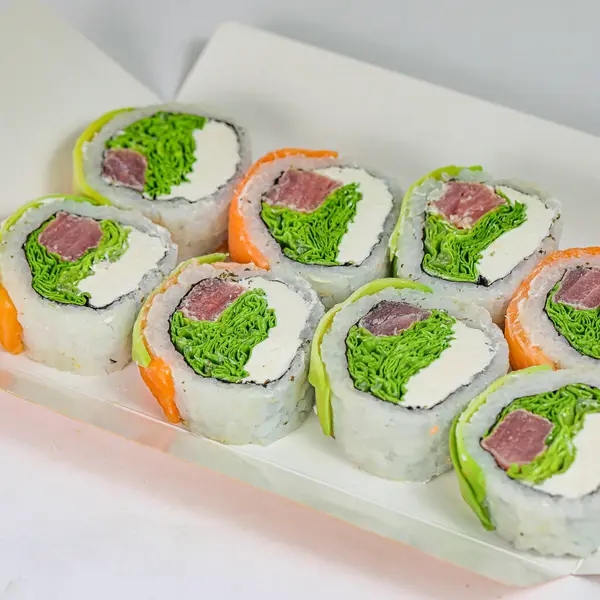 A tray filled with sushi rolls adorned with vibrant green and orange toppings.