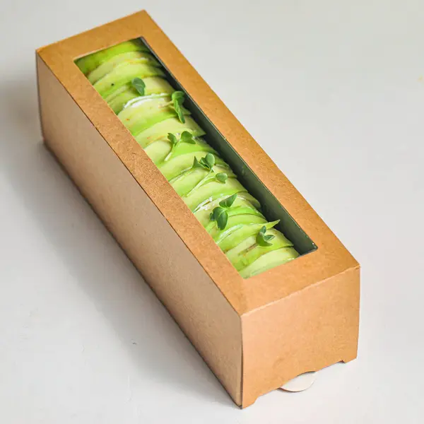 A cardboard box filled with an assortment of fresh green vegetables placed on top of a sturdy table.