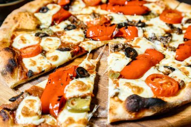 Çeşitli malzemelerle lezzetli bir pizza, sade bir ahşap kesim tahtasının üzerinde güzelce sunuluyor..
